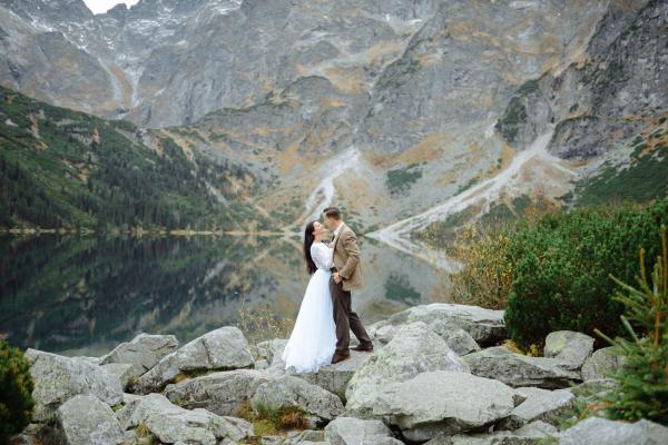 Couple enjoying an intimate moment by a serene lake, surrounded by Banff’s majestic mountain views.